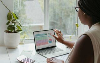 Canada designs new visa for immigrant entrepreneurs image showing dark skin woman in front of a laptop and calculator